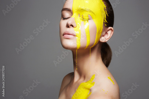 Young woman in Yellow paint. liquid paint flow photo