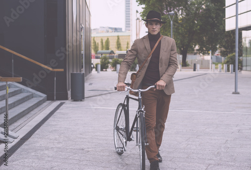 Handsome young business man with his modern bicycle.