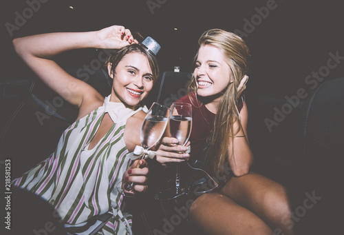 Party girls celebrate in Hollywood drinking champagne on a covertible car