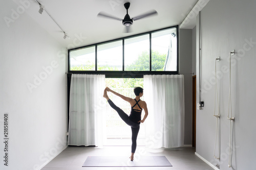 Asian young woman practicing yoga in  gray background.Young people do yoga indoor. © anon