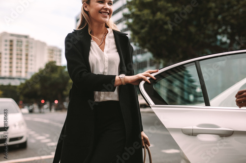 Smiling woman commuter getting out of a taxi