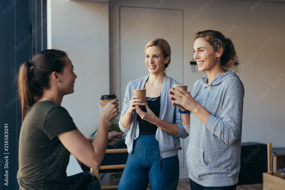 Fitness women drinking coffee after workout in a gym Fitness women drinking coffee after workout in a gym