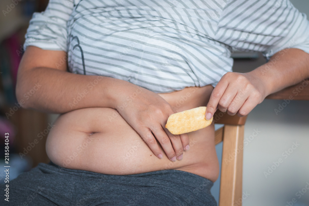Close up hand holding snacked and big belly of woman, Unhealthy concept Close up hand holding snacked and big belly of woman, Unhealthy concept