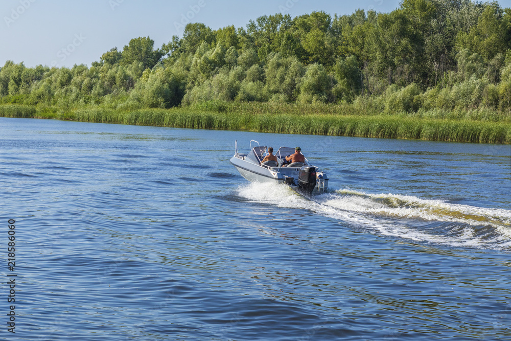 Fototapeta premium Motor boat with people moving on a river