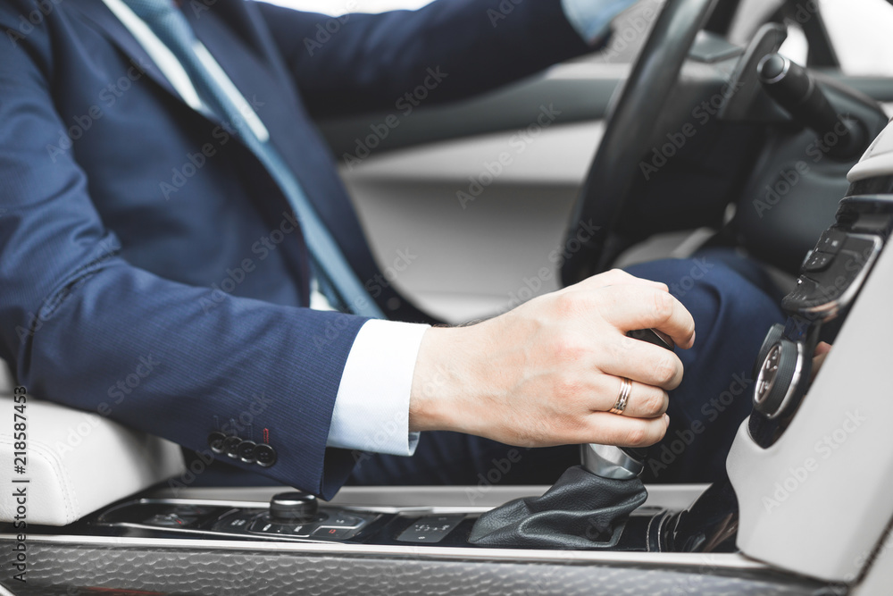 Businessman driving a car. hand close-up on gearbox, gearshift Businessman driving a car. hand close-up on gearbox, gearshift
