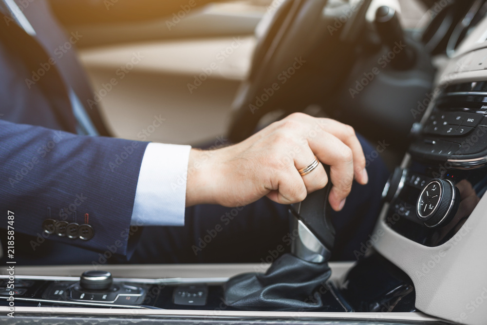 Businessman driving a car. hand close-up on gearbox, gearshift Businessman driving a car. hand close-up on gearbox, gearshift
