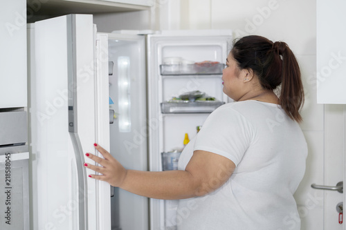 Overweight woman opening a fridge