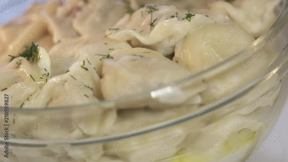 Bowl of homemade boiled dumplings with butter rotating inside microwave. Traditional Russian dish pelmeni filled with meat. Bowl of homemade boiled dumplings with butter rotating inside microwave. Traditional Russian dish pelmeni filled with meat.