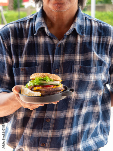 A man holding Double hamburger with onion sweet pepper lectuce cheese bacon and mayonase photo