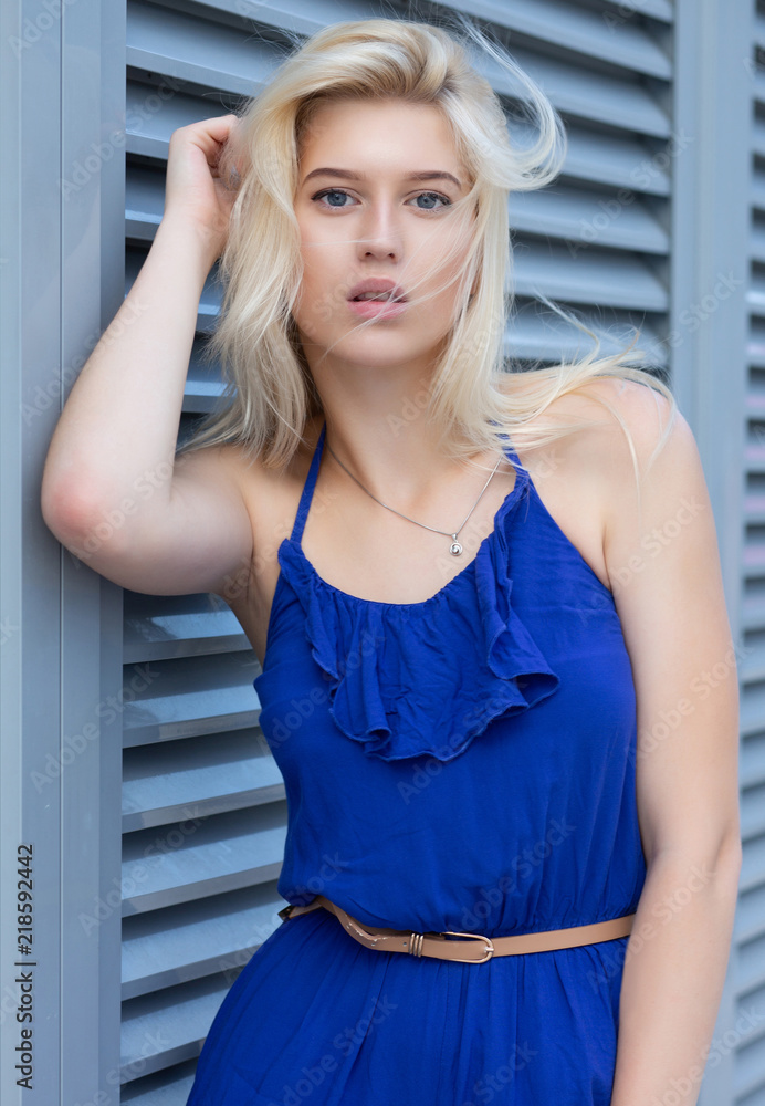 Lovely blonde woman in fashionable romper posing near the metal shutters at the city Lovely blonde woman in fashionable romper posing near the metal shutters at the city
