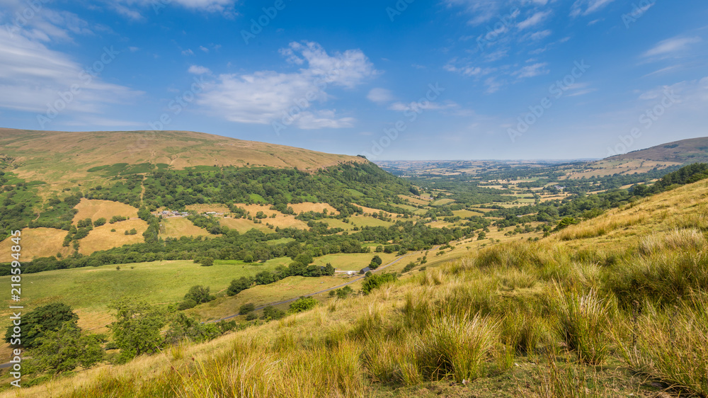 Typical landscape of Brecon Beacons National Park with mountians, trees and hedges along the small roads.