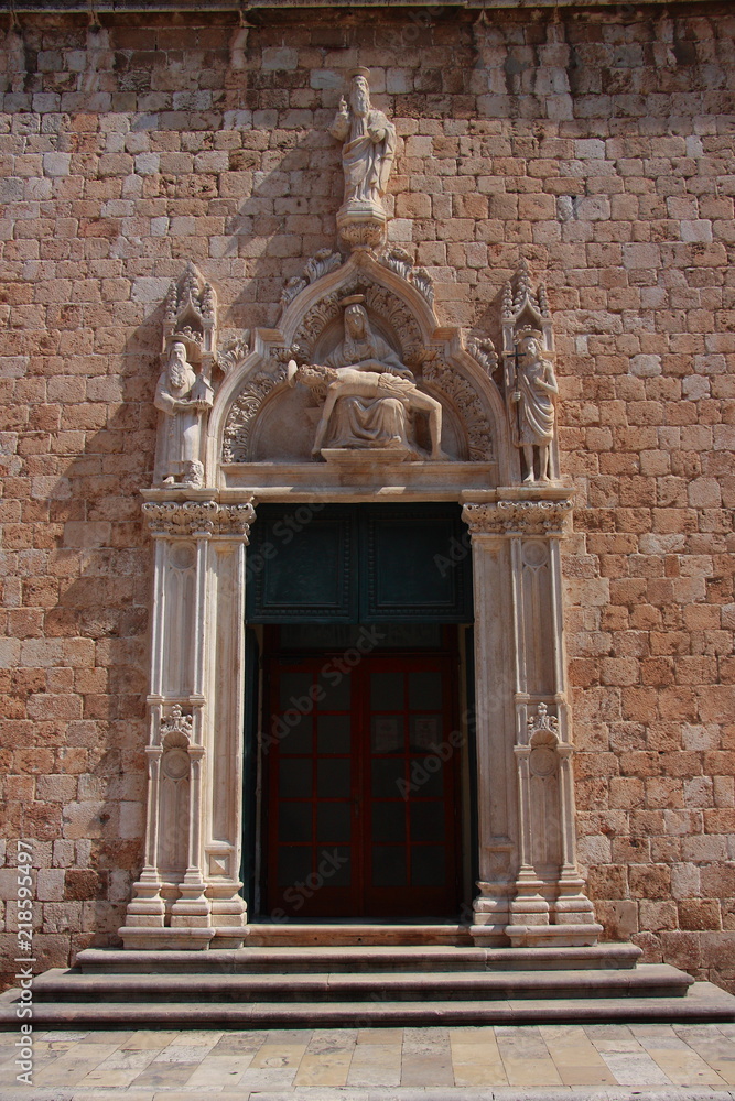Croatia - entrance to the Franciscan church in Dubrovnik with a beautiful portal from 1498 showing the pie - Mother of God with the body of Christ in her lap.