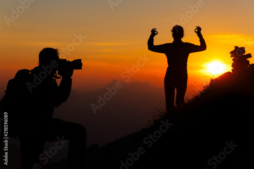 Mountain photographer is a girl with sunset yoga position in silhouettes © michelangeloop