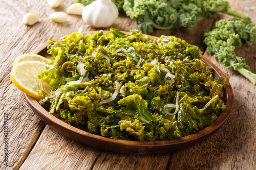Kale or leaf cabbage cooked with onions, garlic, olive oil and lemon close-up on a plate. horizontal