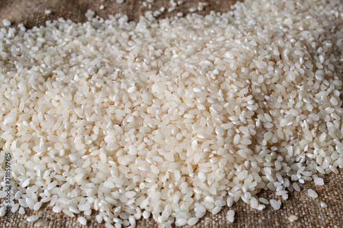 Raw rice is scattered on sackcloth. Uncooked food. selective focus