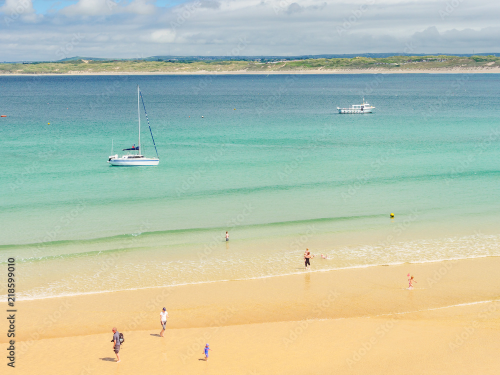 Families enjoying paddling in the sea at Porthminster Beach, in St Ives, on a hot Summer day.