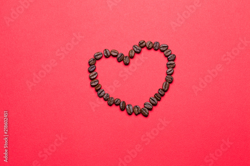 Grains of coffee in the form of heart on a red background