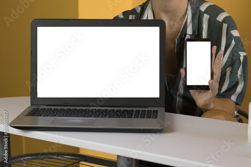 Woman using laptop and smartphone with blank screen  photo