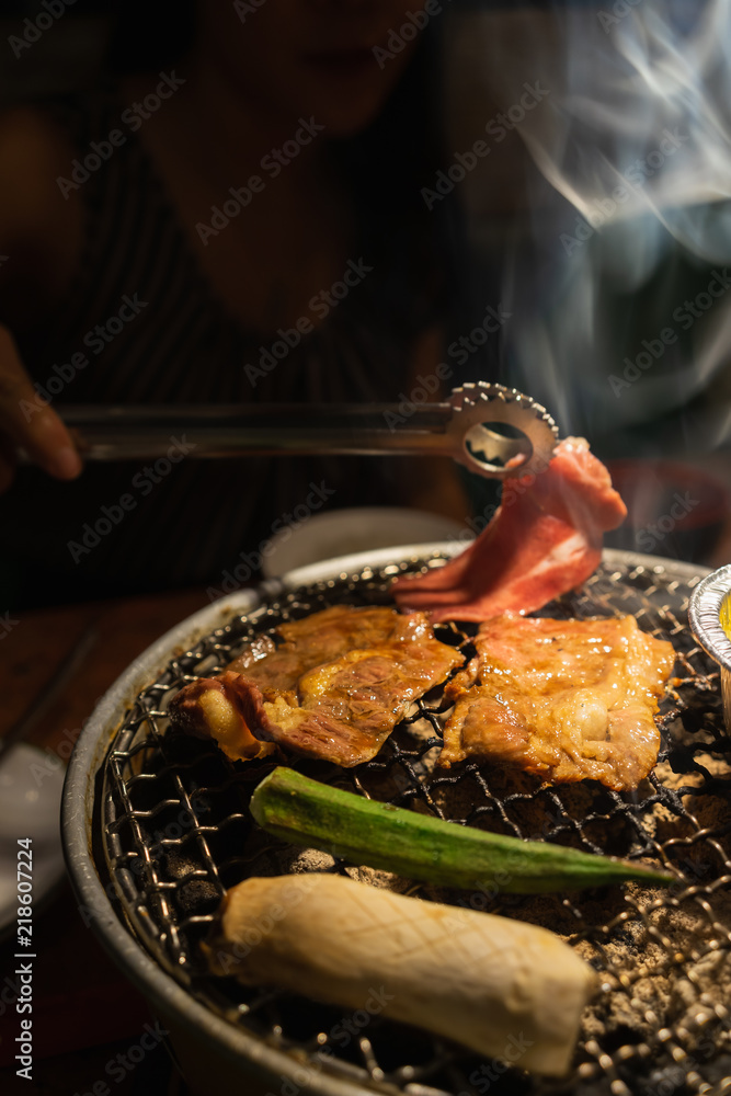 Asian woman with beef barbecue on the grill. Japanese and Korean Food concept.