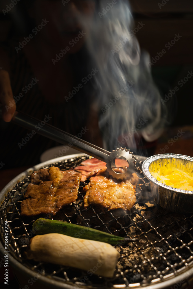 Asian woman with beef barbecue on the grill. Japanese and Korean Food concept.