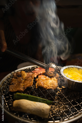 Obraz na płótnie Asian woman with beef barbecue on the grill. Japanese and Korean Food concept. w salonie