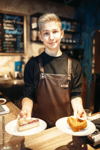 Barista holding in hands plates with sweet dessert