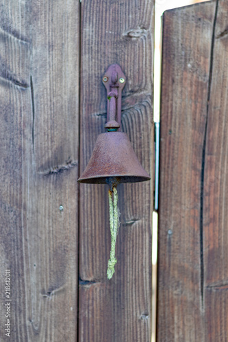 Single iron bell hanging at a wooden door