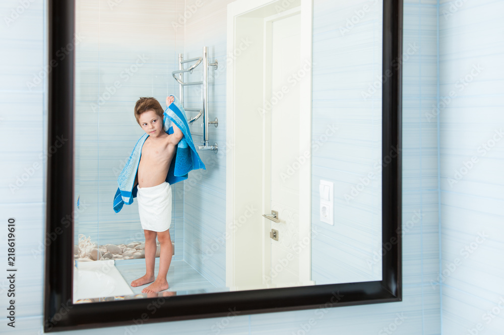 adorable healthy small child dry off his body with blue towel in morning bathroom