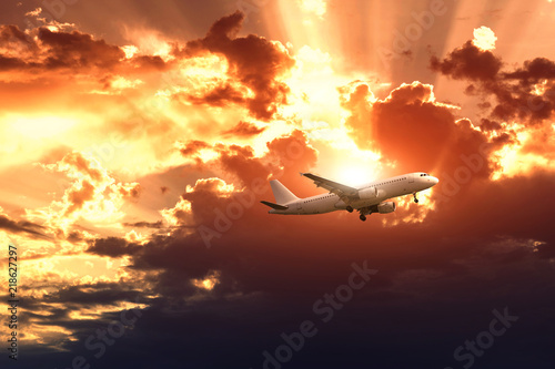 Airplane on the rainy cloudy sky background. The sun's rays make their way through the clouds. 