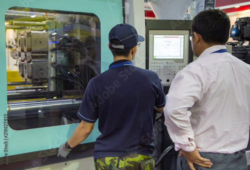 Industrial technician operate injection molding press machine. Industrial plastic manufacturing photo