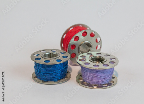 Three sewing machine bobbins with colorful thread