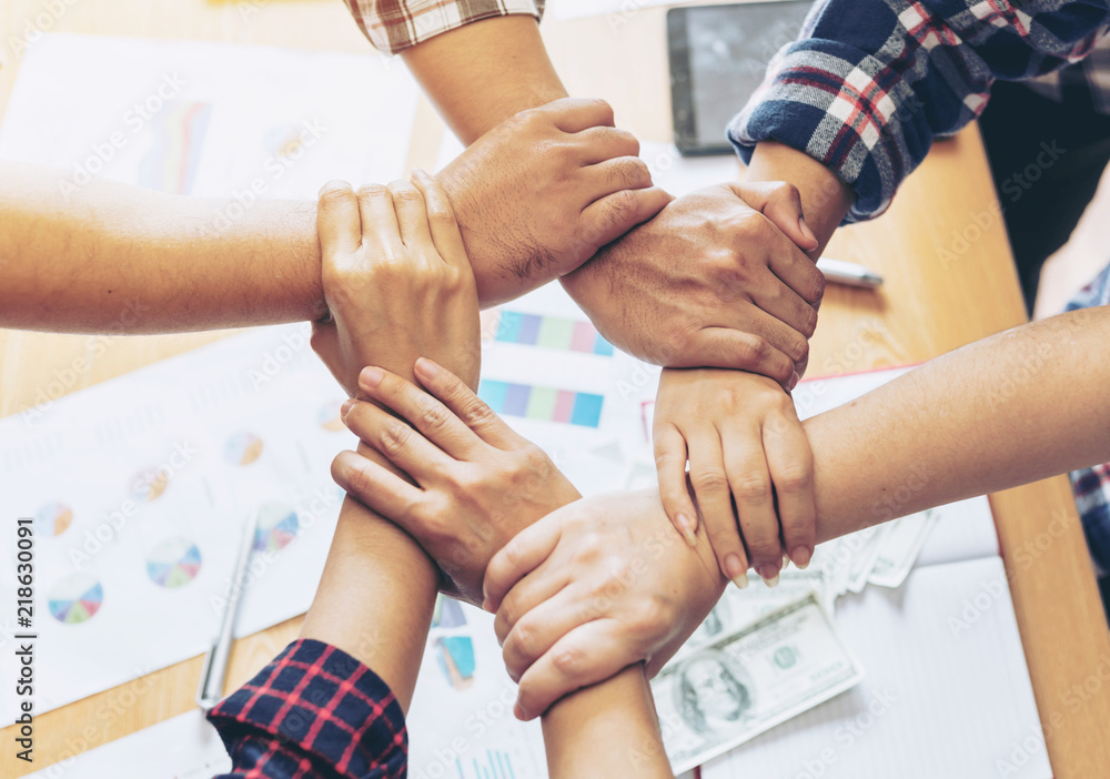 Obraz premium close up hand of business partnerships people crossed hands finishing up meeting showing unity over office desk , business teamwork concept