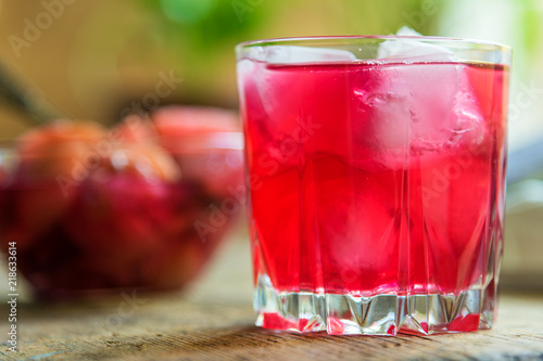 Red fruit drink with ice on a rustic background