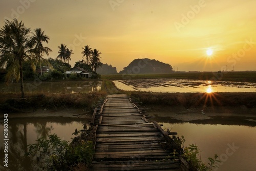 Landscape view of paddy fields,small village,mountain,bridge,river during sunset.