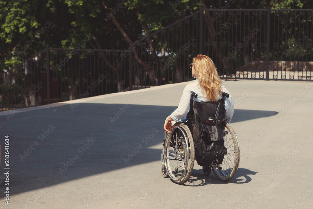 Woman in a wheelchair in the city park. The concept of an accessible environment for disabled people. Woman in a wheelchair in the city park. The concept of an accessible environment for disabled people.