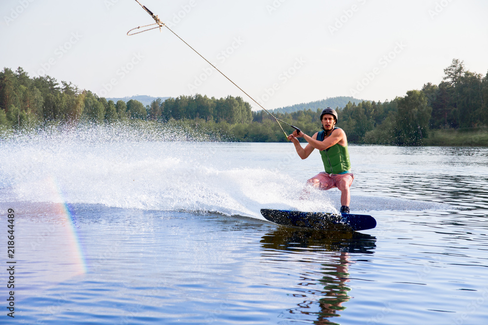 Fototapeta premium Young man riding wakeboard on a lake