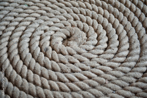 Old gray rope put in spiral. Twisted rope on wooden background.