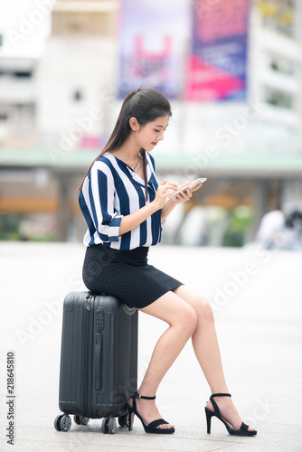 Portrait of Attractive Business Working Woman Using Smartphone with Smile and Sitting on Luggage - Urban Lifestyle Concept