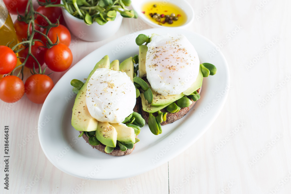 Avocado toast, cherry tomato on wooden background. Breakfast with toast avocado, vegetarian food, healthy diet concept. Healthy sandwich with avocado and poached eggs. Avocado toast, cherry tomato on wooden background. Breakfast with toast avocado, vegetarian food, healthy diet concept. Healthy sandwich with avocado and poached eggs.