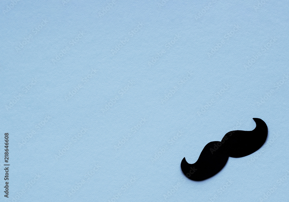 Black mustache on light blue background for Movember concept which is an annual event involving the growing of moustaches during the month of November to raise awareness of men's health issues.
