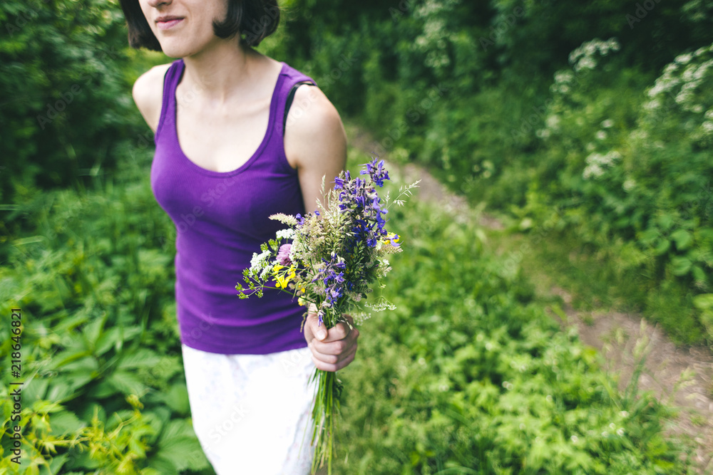 The girl is holding a bouquet of wildflowers. The girl is holding a bouquet of wildflowers.