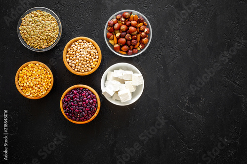 Products rich protein. Legumes, nuts, low-fat cheese. Raw beans, chickpeas, lentil, almond, hazelnut on black background top view copy space