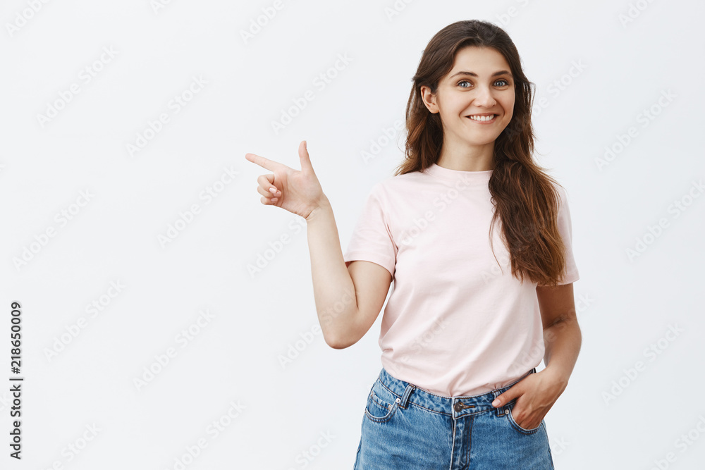 You should check out copy space. Pleased charming and friendly brunette girl in trendy jeans and t-shirt holding hand in pocket pointing left and smiling with satisfied smile giving good advice You should check out copy space. Pleased charming and friendly brunette girl in trendy jeans and t-shirt holding hand in pocket pointing left and smiling with satisfied smile giving good advice
