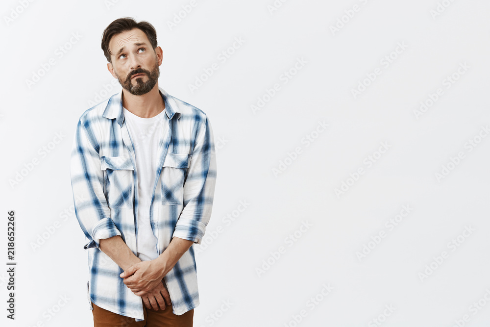 Guy cannot please wife like used to. Portrait of miserable and gloomy european male model with beard and moustache, frowning and gazing with sad look up, holding palms together on pants Guy cannot please wife like used to. Portrait of miserable and gloomy european male model with beard and moustache, frowning and gazing with sad look up, holding palms together on pants