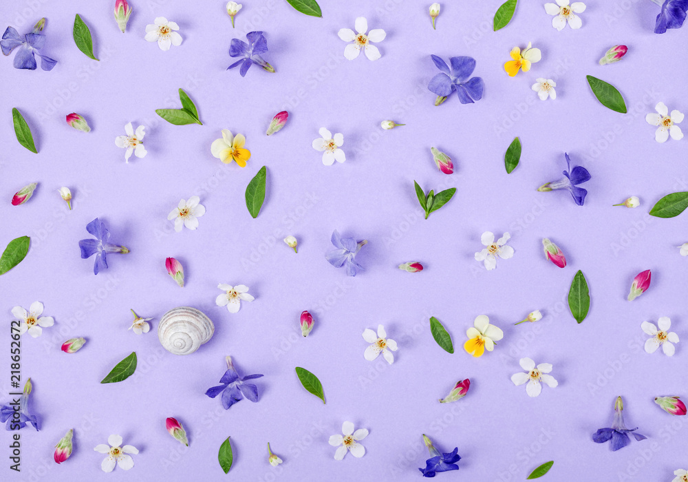 Floral pattern made of spring white and violet flowers, green leaves, pink buds and snail shell on pastel lilac background. Flat lay. Top view. Floral pattern made of spring white and violet flowers, green leaves, pink buds and snail shell on pastel lilac background. Flat lay. Top view.