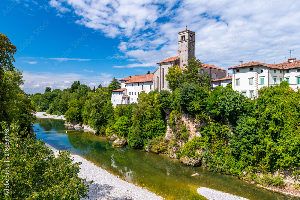 Cividale del Friuli, Italy: View of the old city center with traditional architecture. River Natisone with transparent water. Summer day and blue sky with clouds.