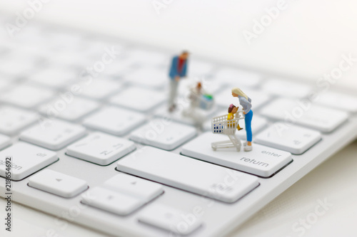 Miniatrue people: Shoppers with shopping cart standing  on keyboard. Shopping online and business concept. photo