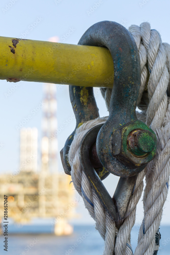 Naklejka premium A green shackle secured on a handrail with a nylon rope on a construction barge at oilfiled