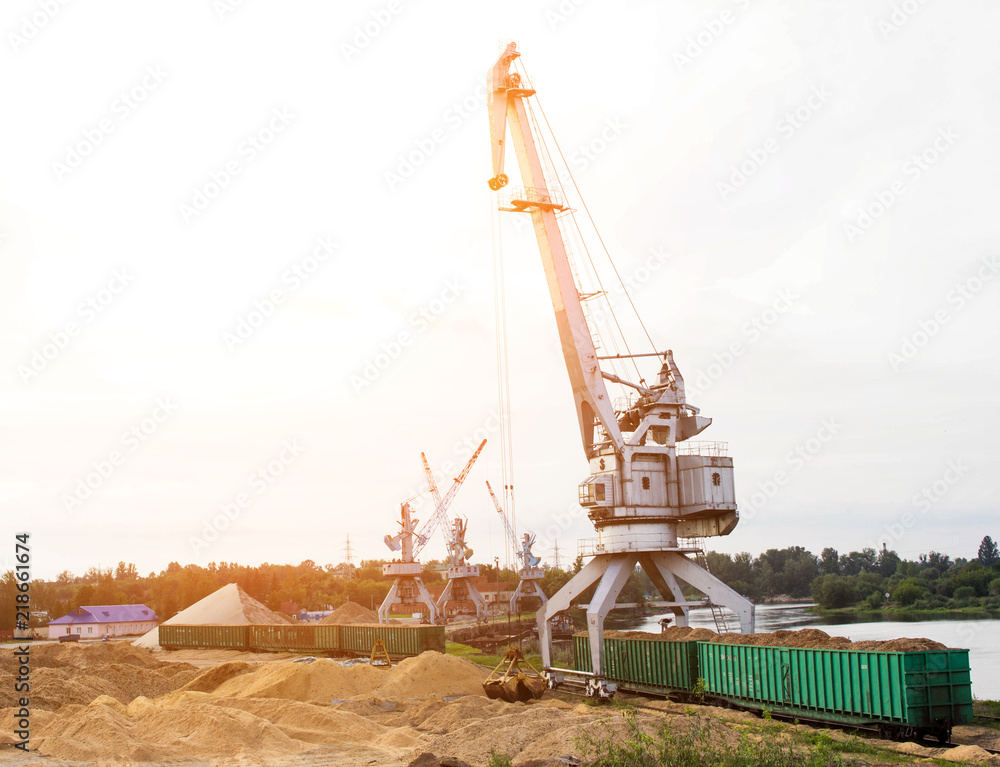 The port crane makes loading of wood chips into the freight cars of the train, loading