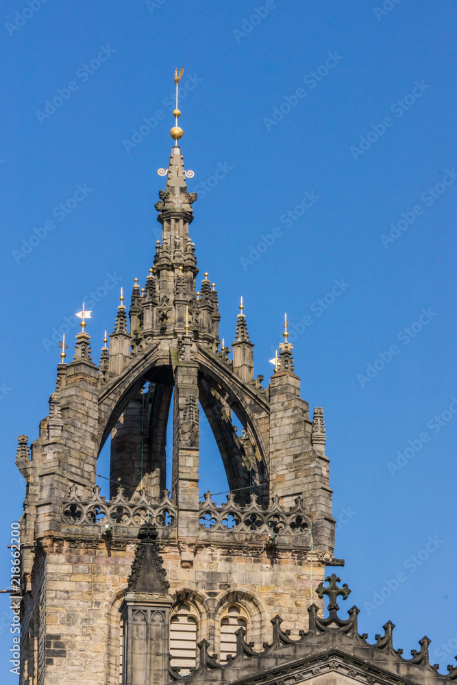 Edinburgh, Scotland, UK - June 13, 2012; St Giles Cathedral. Closeup of crowned spire against blue sky with white clouds. Gray stone structure.